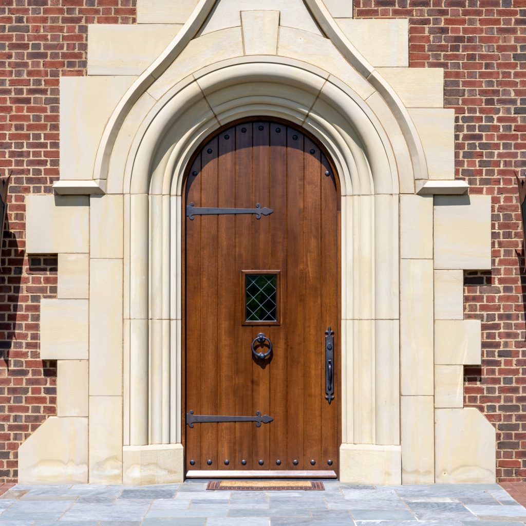 Solid wood arched exterior entry door with leaded glass window and decorative hardware, built by Rockwood Door & Millwork for a Marietta, Ohio estate.