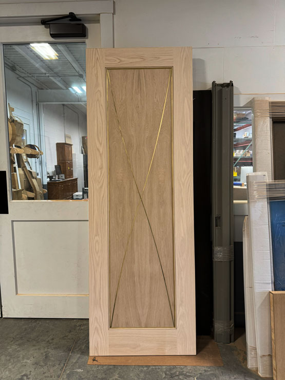 Custom white oak interior door with polished brass inlay detailing, handcrafted by Rockwood Door & Millwork in Millersburg, Ohio.