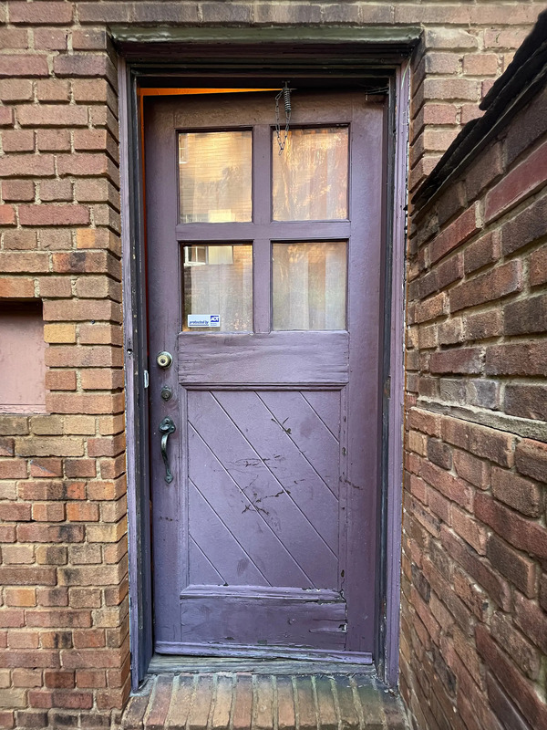 Original pre-war basement door in a Cleveland home showing weathered wood and aged finish before restoration by Rockwood Door and Millwork.