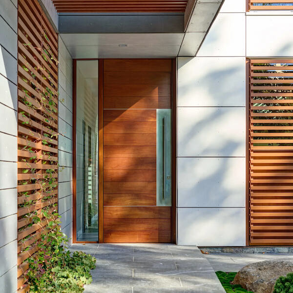 Close-up of the Greenwich Harbor House full-height mahogany door and sidelight, crafted by Rockwood with stainless steel accents and precise horizontal plank alignment.