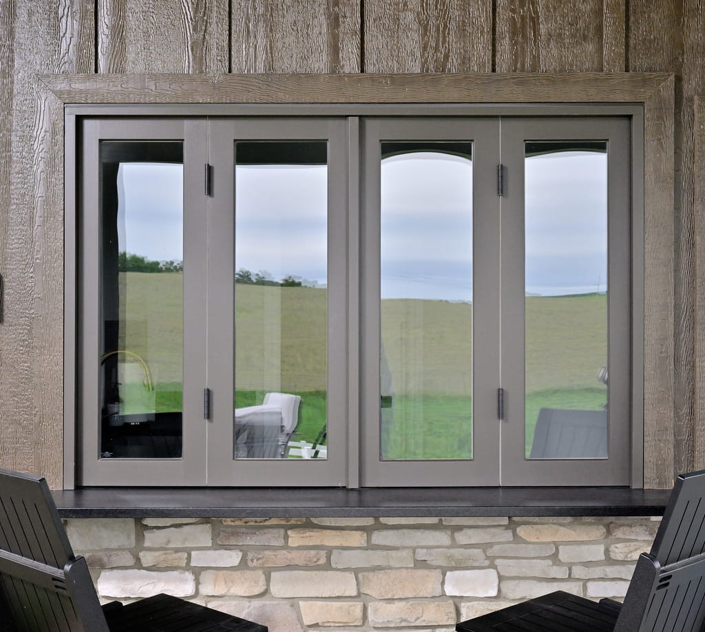 Intro image showing a custom pass-through bifold window with gray frame and stone ledge on a pool house exterior in Ohio.